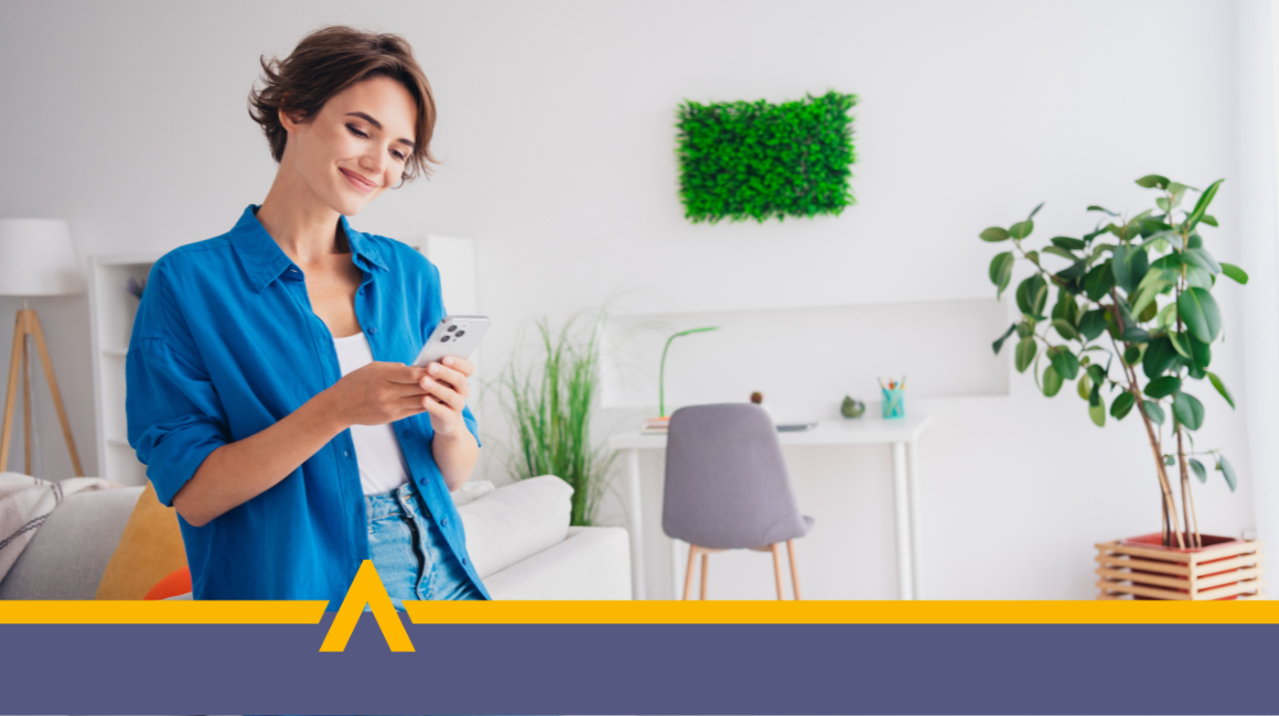 Uśmiechnięta kobieta korzystająca z telefonu w domowym biurze